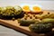 Ingredients for salad - chicken eggs, canned green peas in a black plate and appetizing pickled cucumbers.