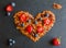 Ingredients in shape of heart to cook a breakfast. Blueberries, strawberries and granola made from oat flakes, dried fruits, nuts