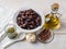 Ingredients for tapenade: dried or cured olives in a white bowl, anchovy fillet, capers, garlic and olive oil on a white rustic