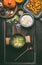 Ingredients of tasty pumpkin dish with rice in cooking pot on dark rustic kitchen table background, top view. Pumpkin risotto prep