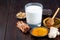 Ingredients for turmeric moon milk on wooden background, horizontal, copy space