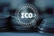 Initial Coin Offering ICO logo led hologram hover over pile stack of regular coins with wired network background.