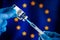 Injecting dose of vaccine in syringe for Covid-19 over the European flag