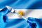 Injecting dose of vaccine in syringe for infections prevention in front of the Argentina flag