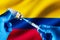 Injecting dose of vaccine in syringe for infections prevention in front of the Colombia flag