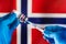 Injecting dose of vaccine in syringe for infections prevention in front of the Norwegian flag