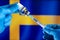 Injecting dose of vaccine in syringe for infections prevention in front of the Swedish flag