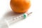 Injecting with a syringe into a tangerine on white background