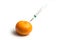 injecting with a syringe into a tangerine on white background