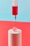 Injection of syringe with red liquid into small ball on cylinder.