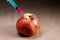 Injection with a syringe into a rotting apple. Close-up. Soft focus