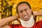 Injured black hispanic male wearing neck brace, holding hands in pain around support making faces of agony, yellow