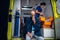 Injured man in a blanket breathing through an oxygen mask in an ambulance car, nurse packing medical equipment in the