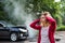 An injured young woman standing by the damaged car after a car accident.