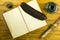 Inkwell from green glass, open book, document in a scroll, feather and candle on a wooden background