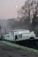 An inland vessel lies in the river on a foggy morning