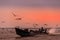 Inle Lake, Myanmar - February 2020: Long-tail boat, a flock of gulls and and beautiful orange/pink sunset sky