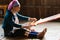 Inle, Myanmar - March 2019: Kayan Lahwi tribe long neck woman sits behind the loom