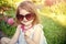 Innocence, purity and youth. Girl in sunglasses sitting in park on floral environment