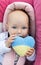 innocent baby with an expressive look holds a knitted yellow-blue Ukrainian heart in hands