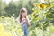 Innocent girl standing by sunflower plants at farm