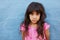 Innocent little girl standing against blue wall