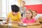 Inquisitive preteen boy peeking at workbook of cute smiling girl in class