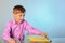 An inquisitive teenager hugs books while sitting at a desk