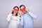 Insanely amazing couple of lovers holding red cardboard hearts in hands near their eyes, feast of St. Valentine