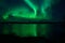 Insanly strong aurora borealis over arctic fjord and mountain landscape in the northern norway