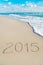 Inscription 2015 on sea sand beach with the sun rays