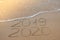 Inscription 2019 and 2020 on beach sand, wave covering 2019 digits. New Year 2020 coming concept