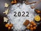 the inscription 2022 on a dark. next to tangerines, orange, cinnamon, caramel, cookies in the form of a Christmas tree