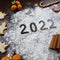 the inscription 2022 on a dark. next to tangerines, orange, cinnamon, caramel, cookies in the form of a Christmas tree