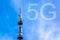 Inscription 5G and telecommunication, cellular tower Radio tower with 5G network against blue bright sky