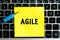 inscription `AGILE` management methodology on a yellow sheet of sticker paper on the background of a computer keyboard