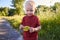 The inscription Autumn is written on a leaf in the hands of a two-year-old funny boy