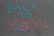 Inscription back to school on black chalkboard. Colored crayons on school black board