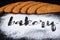 Inscription bakery on white wheat flour scattered Sliced rye bread on dark background