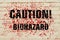 Inscription Caution Biohazard on a bloodstained brick wall.