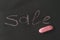 The inscription in chalk pink sale on the black background.