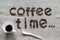 Inscription Coffee Time of a roasted coffee beans on a grey canvas, white cup of ground coffee, white porcelain spoon at bottom,