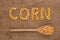 Inscription corn with a wooden spoon on burlap