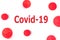 The inscription Covid-19 Coronavirus on a white isolated background with red spotted balls depicting the bacteria of the deadly