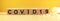 Inscription COVID19 on wooden cubes on a yellow background with pills