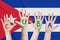 Inscription Cuba on the children`s hands against the background of a waving flag of the Cuba