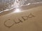 Inscription Cuba on the sandy beach and foamy sea water
