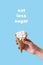Inscription eat less sugar, woman holding in hand ice-cream wafer cone filled with white sugar cubes on blue background