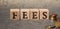 Inscription FEES on wooden cubes on a gray background