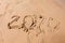 Inscription with a finger on the sand. Figures happy new year 2020.  With traces of people in the sand